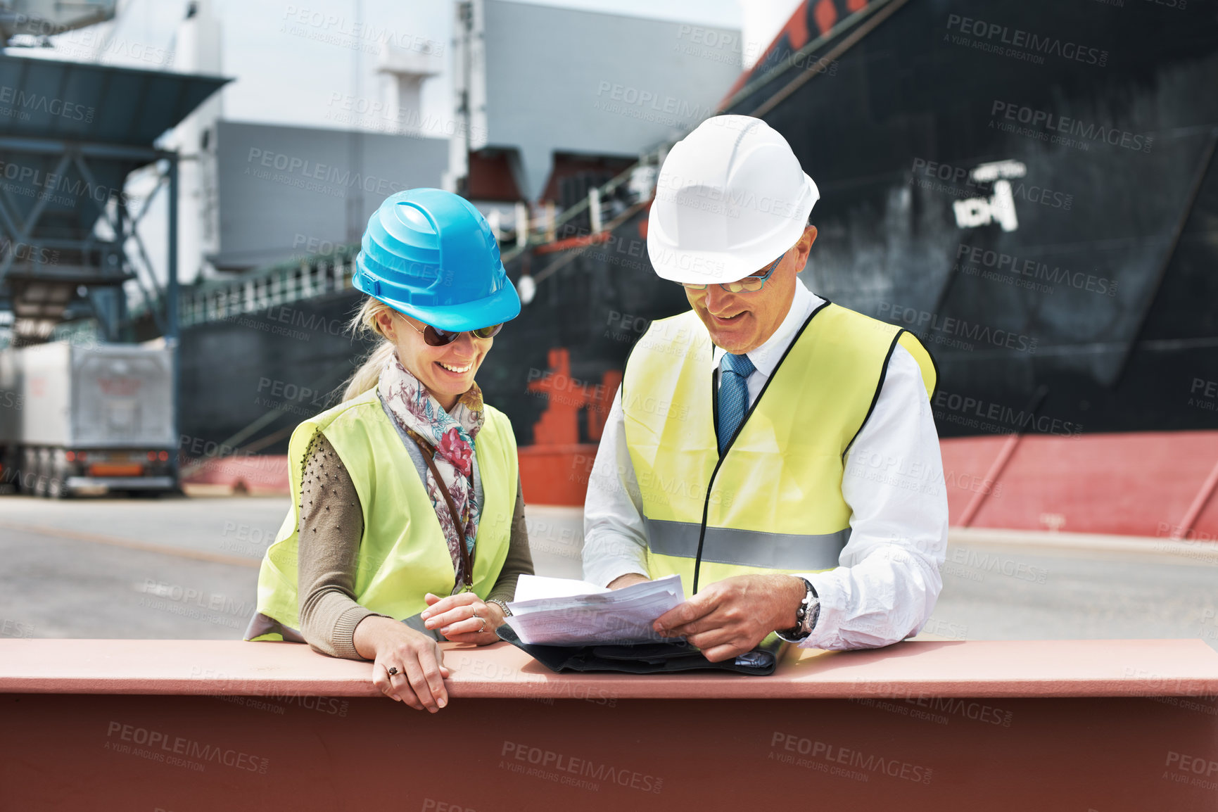 Buy stock photo Two dock workers holding paperwork while standing in the shipyard