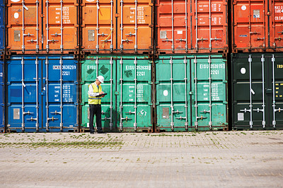 Buy stock photo A customs inspector standing and reviewing a tack of containers