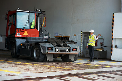 Buy stock photo A manager standing at a loading dock signaling a truck to reverse