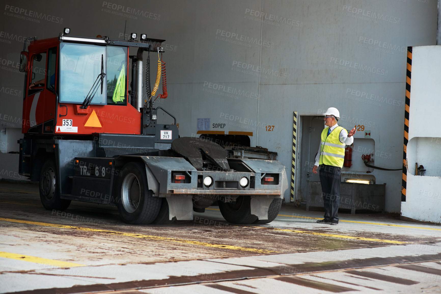 Buy stock photo A manager standing at a loading dock signaling a truck to reverse