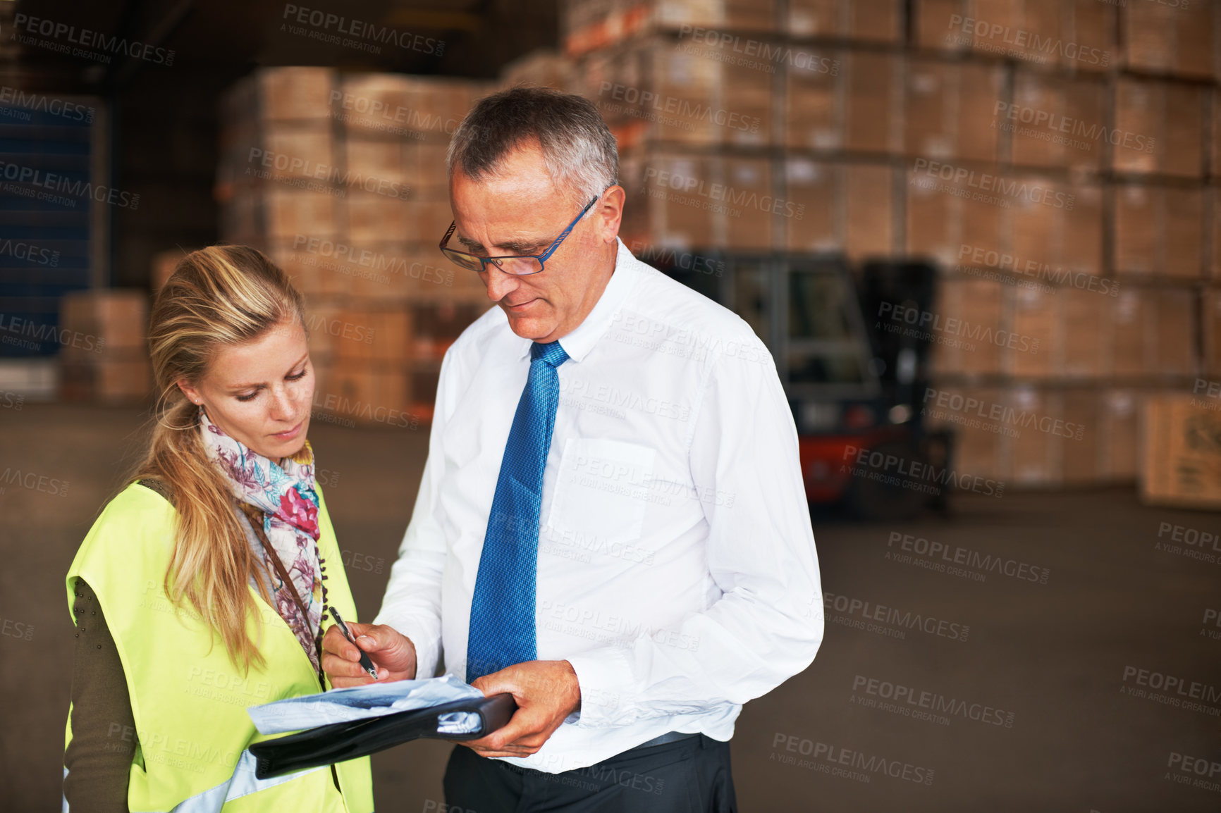 Buy stock photo Two colleagues talking to one another in a warehouse filled with cardboard boxes