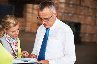 Buy stock photo Two employees discussing a plan while standing in a warehouse.