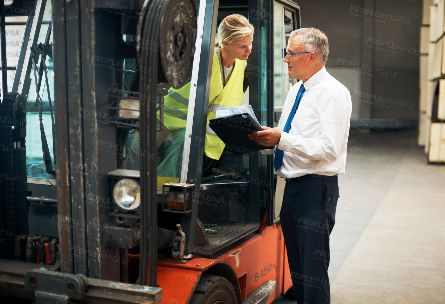 Buy stock photo A manager giving orders to an employee who's sitting on a forklift.