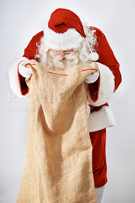 Buy stock photo Santa Claus, bag and gift with a man in a costume posing in studio on a gray background for the holidays. Delivery, Father Christmas and sack with a male in an outfit for festive season celebration
