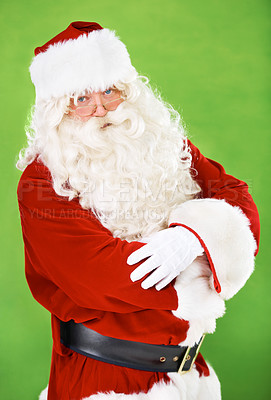 Buy stock photo Christmas, santa and costume with a man in studio on a green background for festive season celebration. Portrait, glasses and serious attitude of saint nick standing arms crossed for the holidays