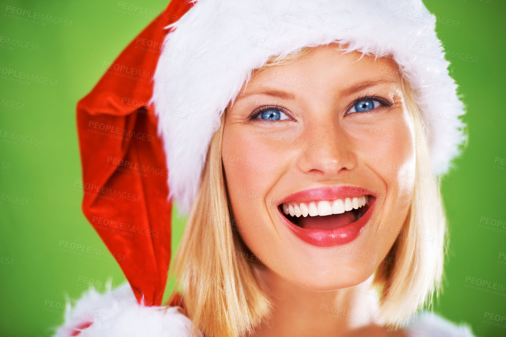 Buy stock photo Face, beauty and christmas with a model woman in studio on a green background for festive celebration. Portrait, happy and smile with an attractive young female wearing a santa hat in the holidays