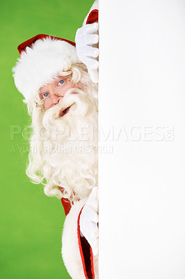 Buy stock photo Santa peeking out around the corner of a white wall, on a green background - copyspace