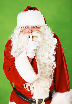 Buy stock photo Santa claus, finger and quiet secret in studio for Christmas surprise, celebration or holiday excitement. Male person, hand gesture and hush emoji for winter vacation joy, green background or mockup