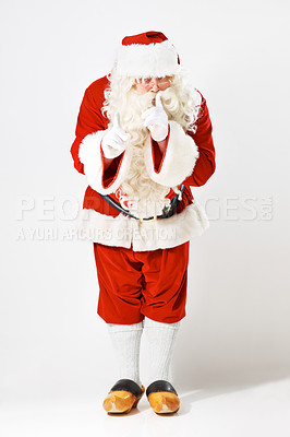 Buy stock photo Christmas, santa claus and man in studio for secret, surprise and exciting good news against a white background mockup. Father christmas, costume and hand sign hush, quiet and festive celebration