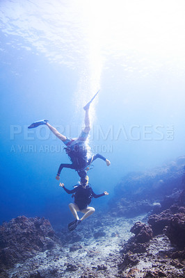Buy stock photo Two buoyant scuba divers fooling around underwater "head to head and upside down" - Copyspace