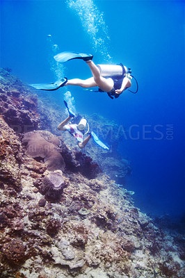 Buy stock photo Couple, swimming and scuba diving in ocean for underwater adventure and explore on tropical holiday or vacation. Sports people, tourist or diver with bubbles, blue water and search sea life or coral