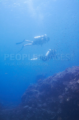 Buy stock photo Couple, swimming and scuba diving in sea for underwater adventure and explore on tropical holiday or vacation. Sports people, tourist or diver with bubbles, blue water and search ocean life or coral
