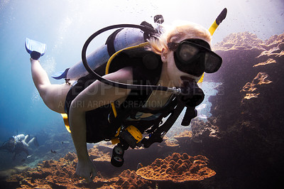 Buy stock photo Female scuba diver closely passes over a coral reef