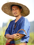 Portrait of a Thai rice farmer holding a scythe and wearing a traditional hat