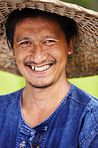 Closeup portrait of a Thai rice paddy worker wearing a traditional hat