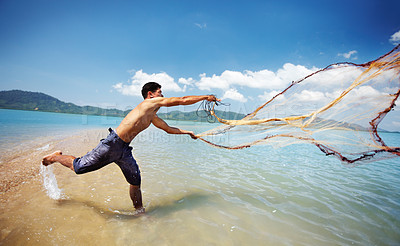 Buy stock photo Shot of a traditional thai fisherman standing in the water casting a net into the ocean
