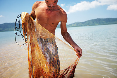 Buy stock photo Shot of a traditional thai fisherman standing in the water holding a net