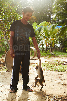 Buy stock photo Smile, man with monkey and pet holding hands at forest, jungle and outdoor in nature in summer. Person, friendship and trainer with macaque at park, wilderness and tropical zoo or shelter in Thailand
