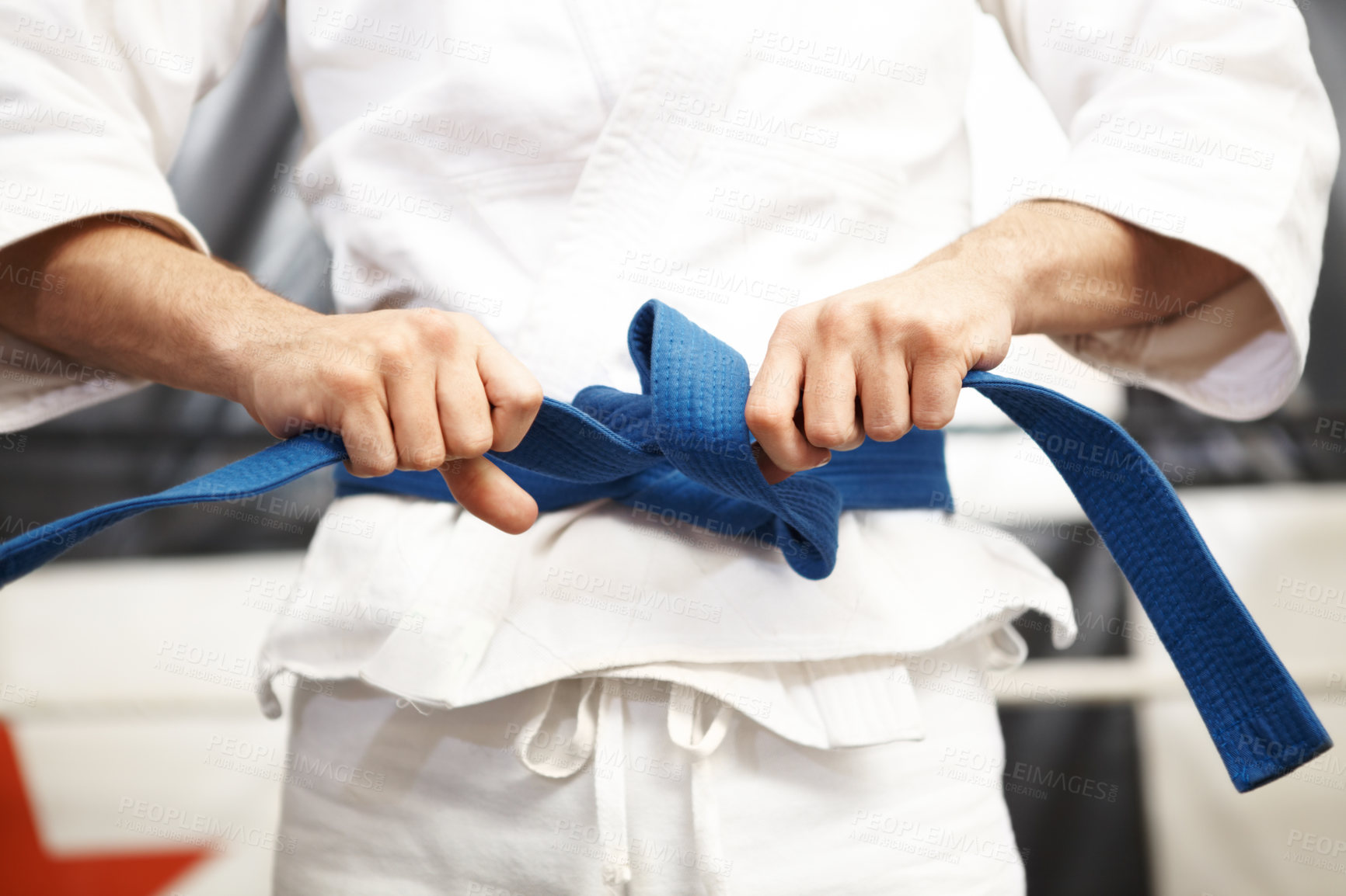 Buy stock photo Cropped shot of martial artist putting on his gi and tying his belt