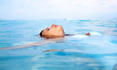 Buy stock photo Shot of a beautiful young woman swimming in blue ocean