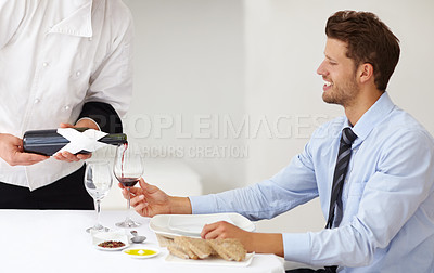 Buy stock photo Handsome young man smiling as a sommelier pours wine for him at a restaurant - Fine Dining