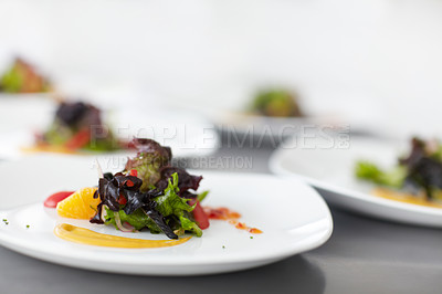 Buy stock photo Closeup of fresh green salad served on white plates in fine dining restaurant. Zoomed in macro with copyspace of healthy prepared food ready to be eaten for lunch. Delicious meal on kitchen counter