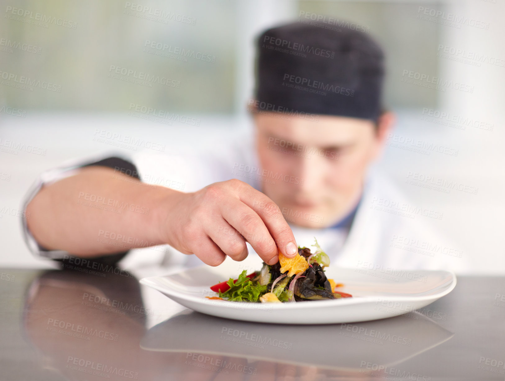 Buy stock photo Young chef putting the final perfect touches to his superbly prepared dish
