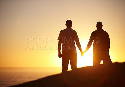 Buy stock photo Silhouette, sunset and a gay couple at the beach holding hands for bonding, love and a date. Back, dark and lgbtq men with care, support and watching the view at the ocean or sun on a vacation