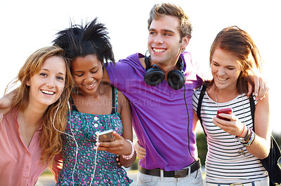 Buy stock photo Closeup of four friends listening to music and typing on their cellphones