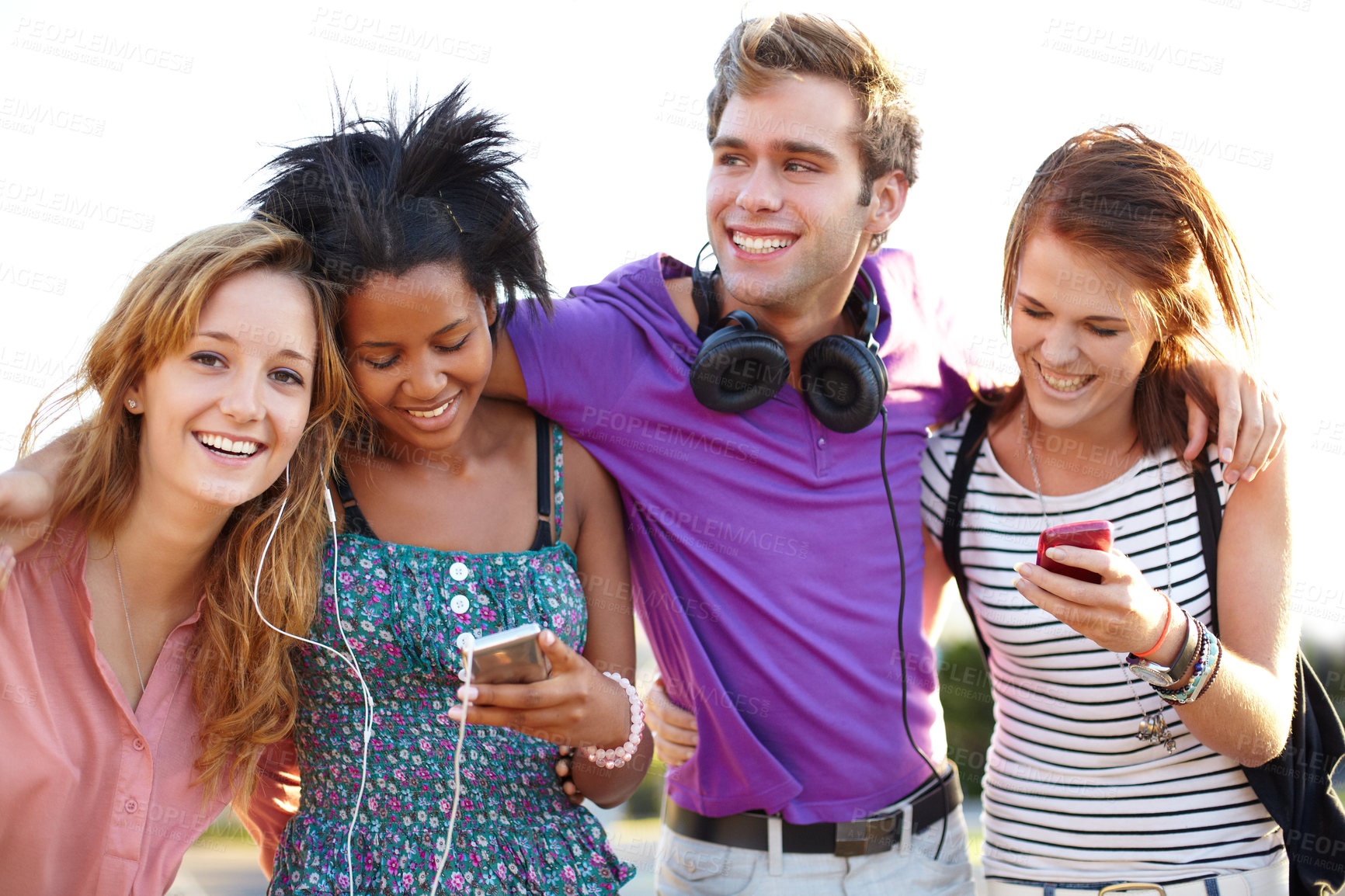 Buy stock photo Closeup of four friends listening to music and typing on their cellphones