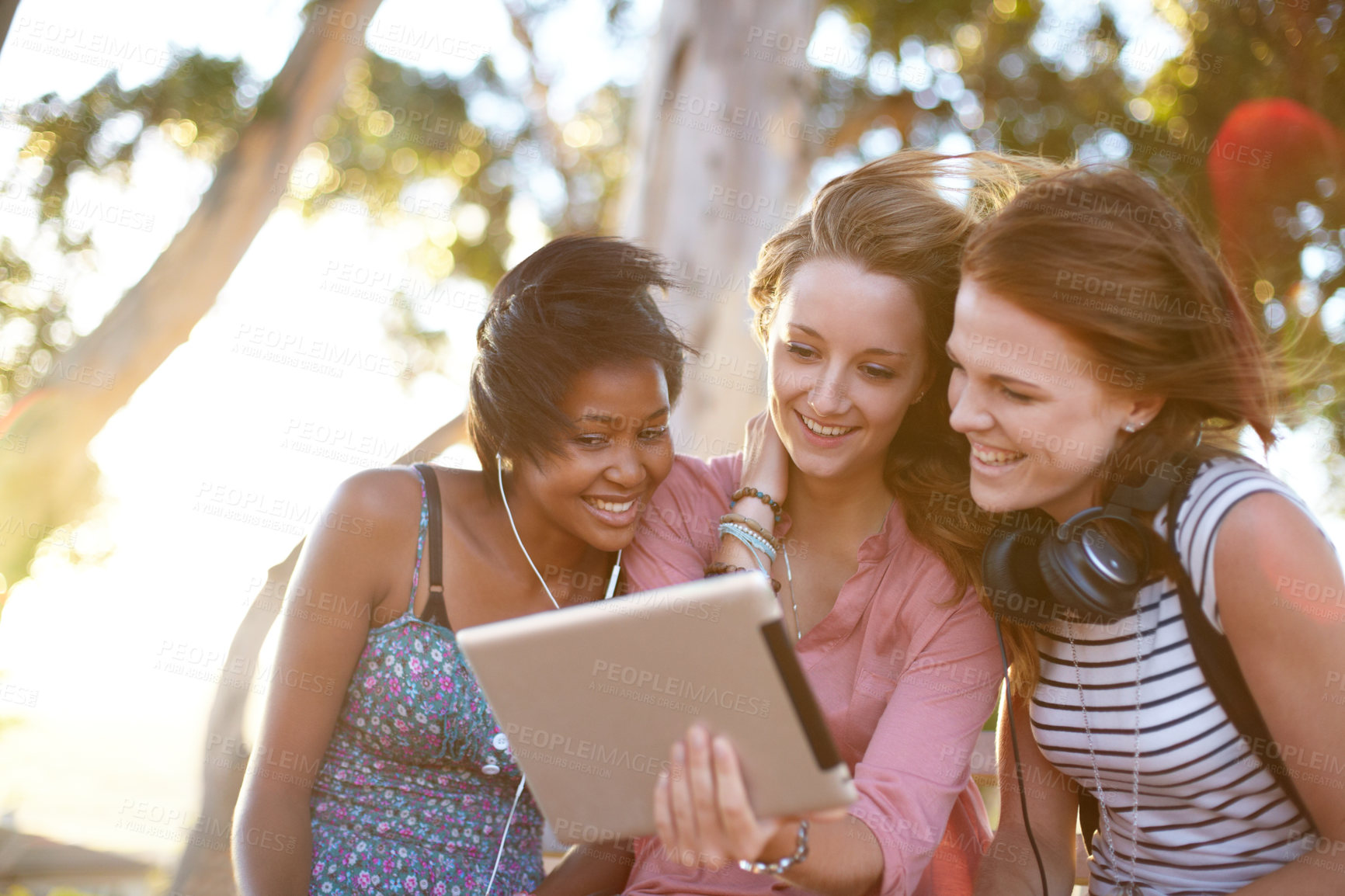 Buy stock photo Three young women sitting outside working on a digital tablet