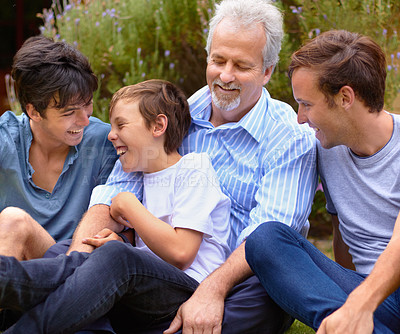 Buy stock photo Father and sons laughing with one another sitting on a lawn