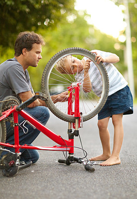 Buy stock photo Young father and son fixing a bicycle tyre puncture