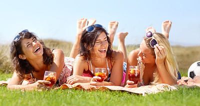 Buy stock photo A group of friends lying on a blanket outside and enjoying a drink together