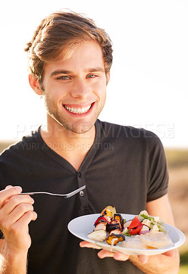 Buy stock photo Portrait, smile and a man eating food outdoor on a summer day for health, diet or nutrition. Happy, morning and lifestyle with a handsome young person enjoying a fresh meal alone outside in nature