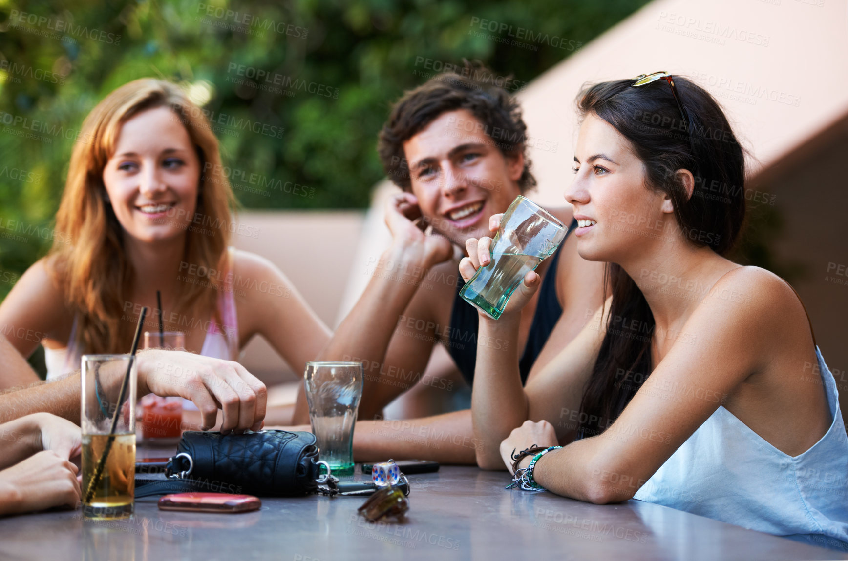 Buy stock photo Friends, bar and drinks during conversation on the weekend for bonding, happiness and social. Table, alcohol and people, men or women speaking at an outdoor restaurant for a group chat or drinking