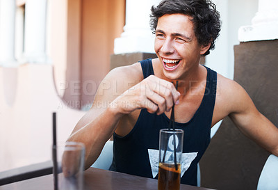 Buy stock photo Handsome young guy laughing while enjoying his cold beverage