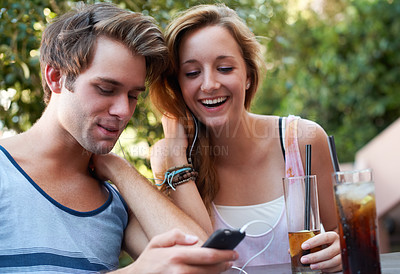 Buy stock photo Cute teen couple sharing an MP3 player and listening to music while enjoying their beverages