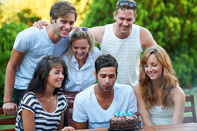 Buy stock photo Birthday, friends and blow candles outdoor for celebration, surprise or party with milestone or happiness. Cake, men and women in backyard of home or nature with gathering or social event with smile