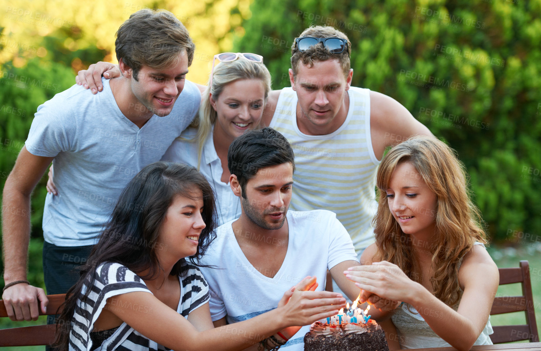 Buy stock photo Happy young teen friends celebrating someone's birthday with a cake and candles
