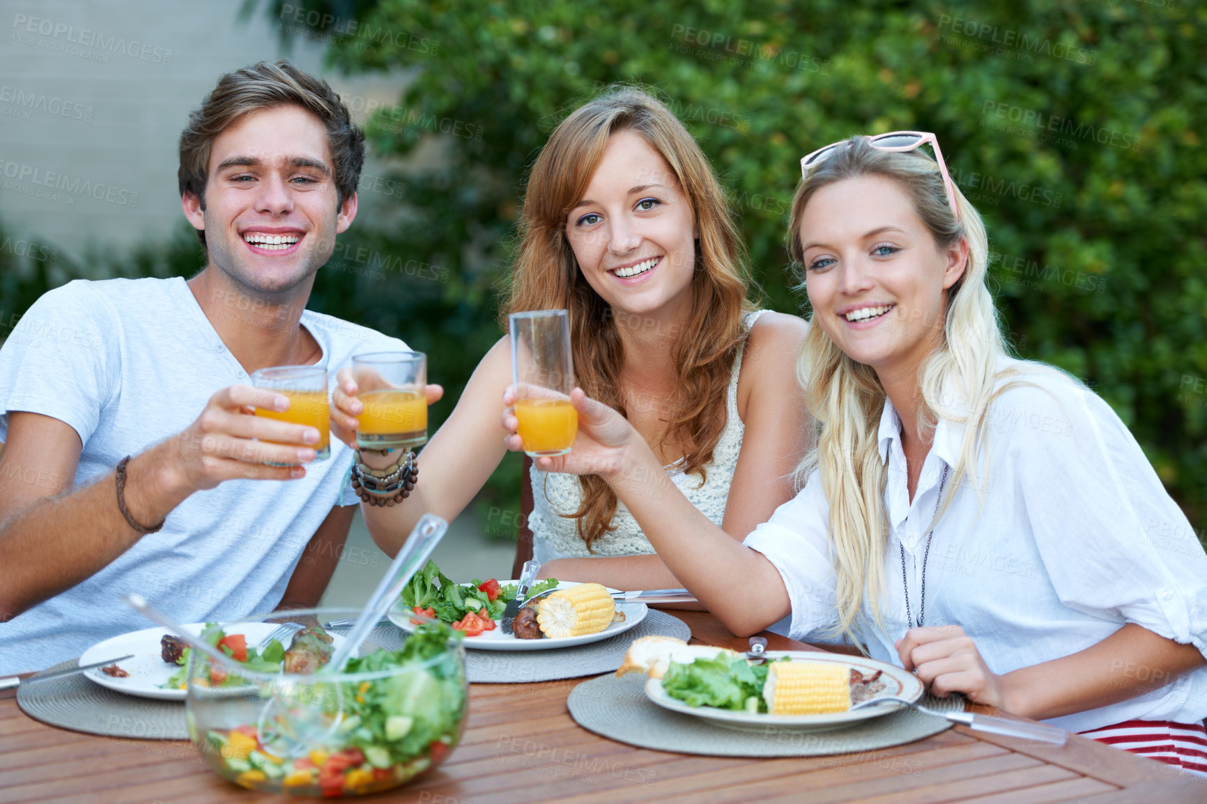 Buy stock photo Friends, portrait and food in backyard with lunch cheers and drinks with a smile with reunion event. Salad, happy and young people outdoor of home with holiday meal and toast with juice ready to eat