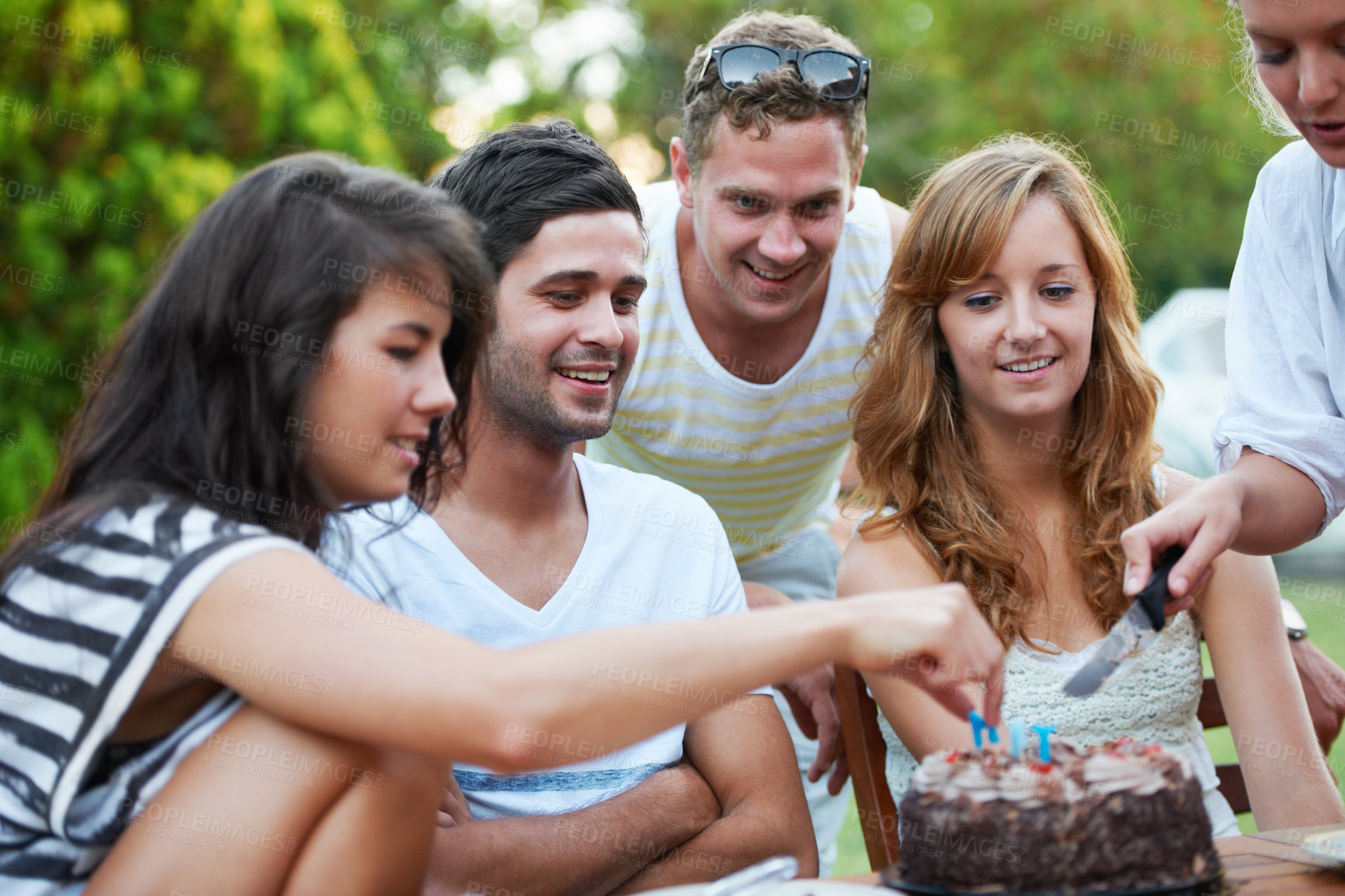 Buy stock photo Smiling young teen friends celebrating someone's birthday and cutting some birthday cake