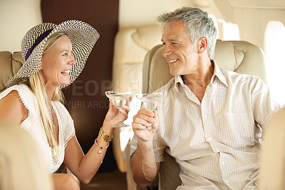 Buy stock photo Smiling and happy couple seated in a private jet and toasting each other