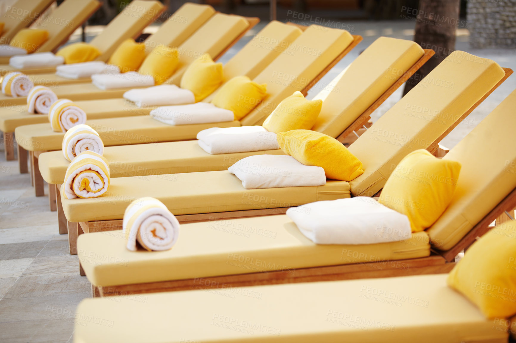 Buy stock photo Closeup row of yellow deckchairs in a line at a travel resort or hotel spa. Comfortable seating when on holiday or vacation by the pool. Towels on pillows on loungers outside poolside at a villa