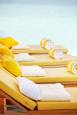 Buy stock photo Closeup row of yellow deckchairs in a line at a resort. When you need seating or a comfortable place to sit when on holiday or vacation by the pool. Towels on pillows on loungers outside at a villa