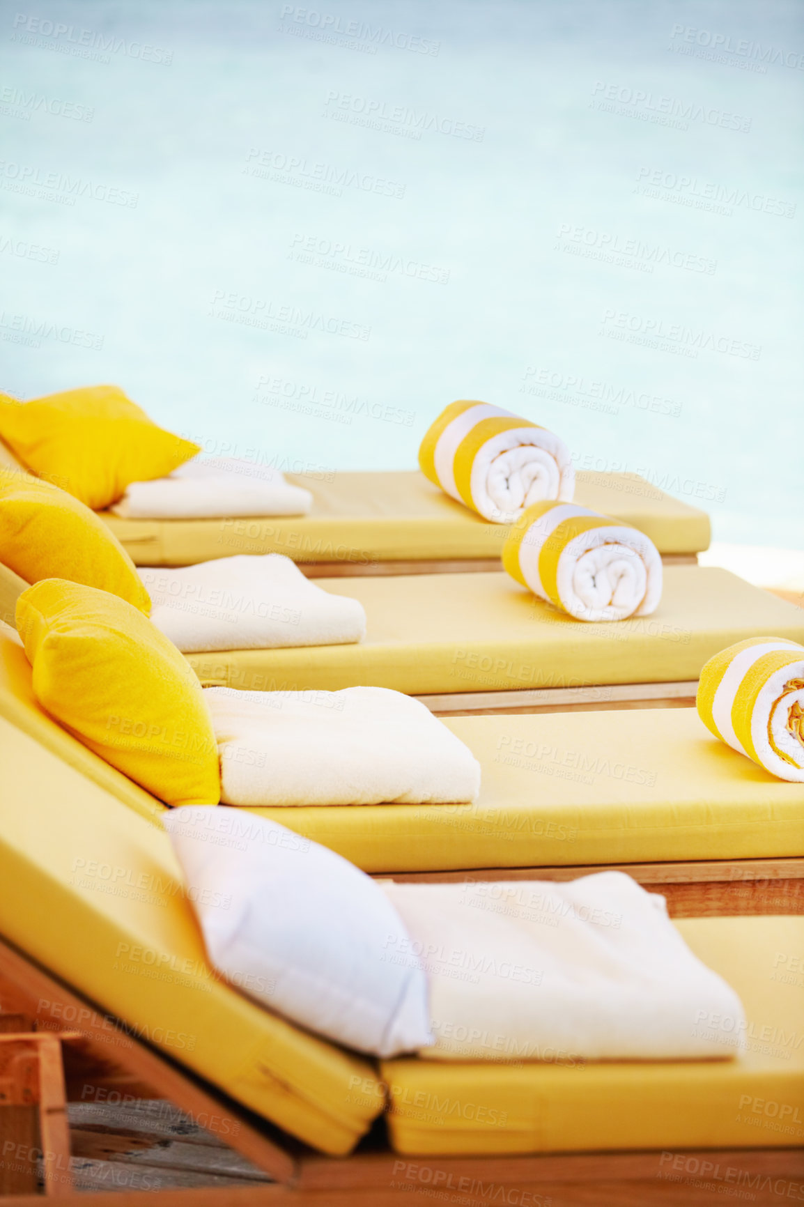 Buy stock photo Closeup row of yellow deckchairs in a line at a resort. When you need seating or a comfortable place to sit when on holiday or vacation by the pool. Towels on pillows on loungers outside at a villa