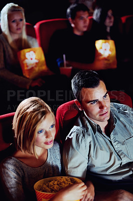 Buy stock photo Cinema, watching and couple with popcorn, film and eating on romantic date together. Movie night, man and woman in theater with snacks, entertainment and sitting in auditorium to relax at premier.