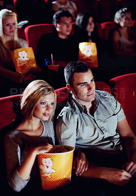 Buy stock photo Cinema, love and couple with popcorn, watching film or eating on romantic date together. Movie night, man and woman in theater with snacks, romance and sitting in auditorium to relax at show premier.