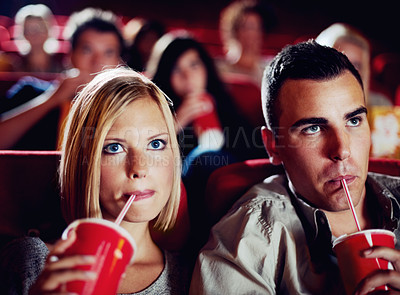Buy stock photo Cinema, movie and couple with drink, watching film and concentration on romantic evening together. Date night, man and woman in theater with soda, attention and sitting in auditorium to relax at show