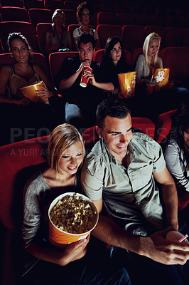 Buy stock photo A happy young couple watching a movie at the cinema together